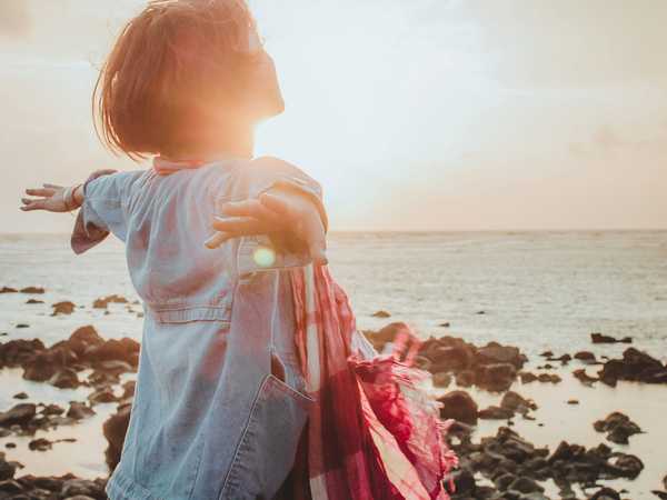 Financial freedom - person with arms outstretched at sunset